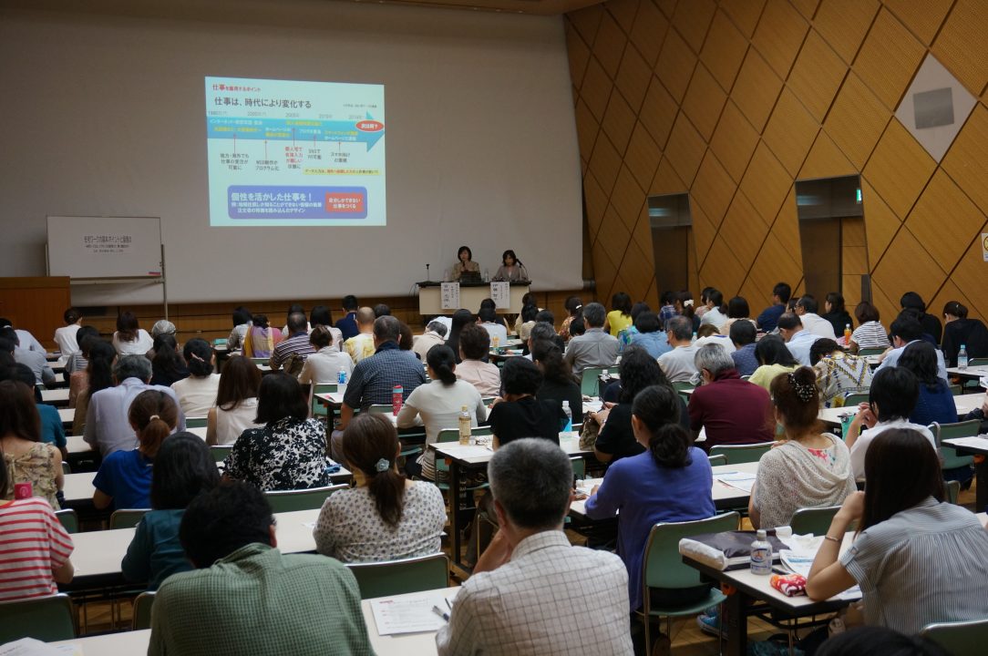 満席の会場で開かれたフラウネッツの在宅ワークセミナー。スクリーンに「仕事は、時代により変化する」のスライドが映っている